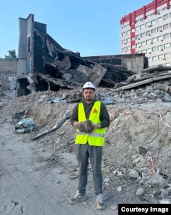 Oleksii Hunyak, from Lviv Polytechnic National University, poses with broken concrete at the site of a Russian strike in Ukraine.